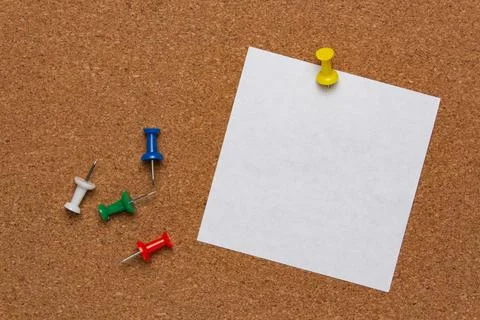 White note sheet pinned on cork board and colored pins Stock Photos