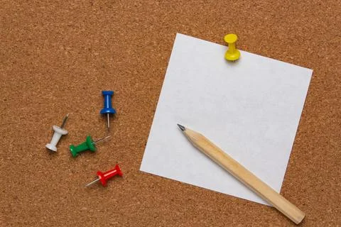 White note sheet pinned on cork board with colored pins and pencil Stock Photos