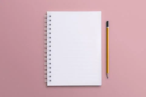A white notebook and pencil placed on a pink paper surface. Stock Photos