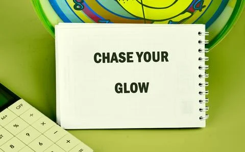A white notebook displays the uplifting message CHASE YOUR GLOW, sitting next to Stock Photos