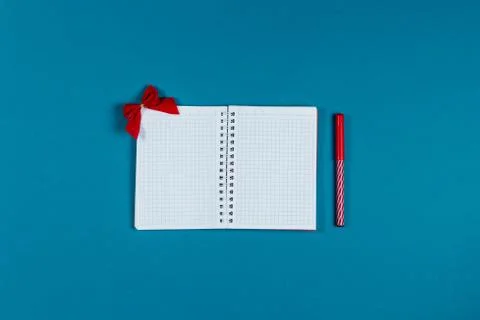 White notebook, red marker and red bow on the blue background. Stock Photos