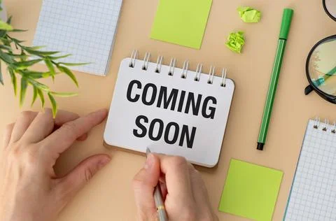 White notebook with text Coming soon on yellow color background. Top view Stock Photos
