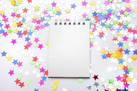 White notebook on a white background with scattered multicolored glitter st.. Stock Photos