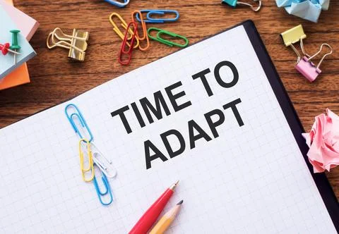 White notebook with the words "Time to adapt" on a beautiful wooden table, .. Stock Photos