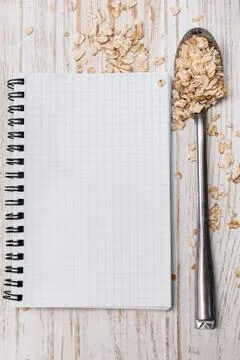 White notepad and spoon with oat flakes on wooden background Stock-Fotos