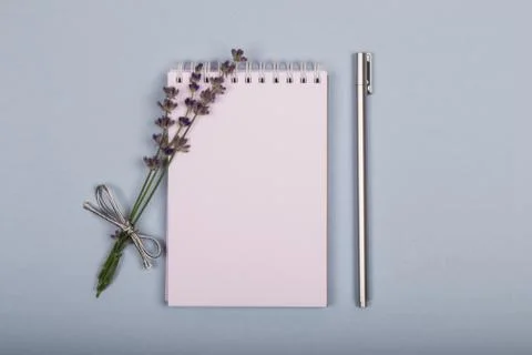 White notepad on a blue background with a small bouquet of purple lavender an 스톡 사진