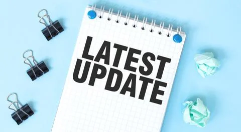 White notepad with text LATEST UPDATE and office tools on the blue background Stock Photos