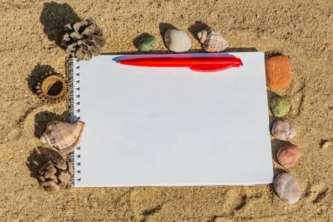 A white notepad with a white spring with a red ball-point pen lies on a yellow Stock Photos