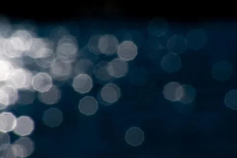 White octagonal bokeh lights reflecting in blue lake water reflections graphic Stock Photos