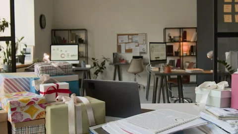 White Office Desk Featuring Laptop, Colourful Gift Boxes and Piles of Documents Stock Footage 331535148