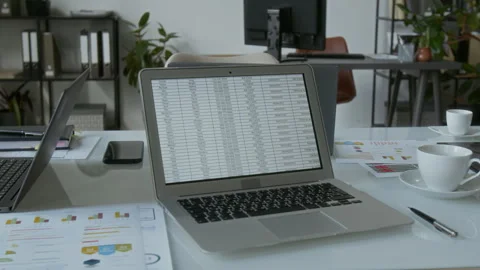 White Office Desk Featuring Open Laptop Displaying Detailed Spreadsheet Stock Footage 312059486