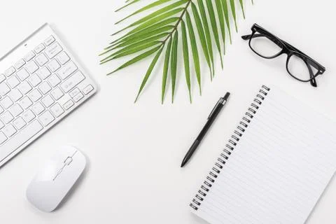 White office desk table with notebook, computer keyboard and office supplies. Stock Photos