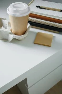 White office desk with working tools and takeaway coffee in paper cup. Corp.. Foto stock