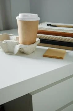White office desk with working tools and takeaway coffee in paper cup. Corp.. Stock-Fotos