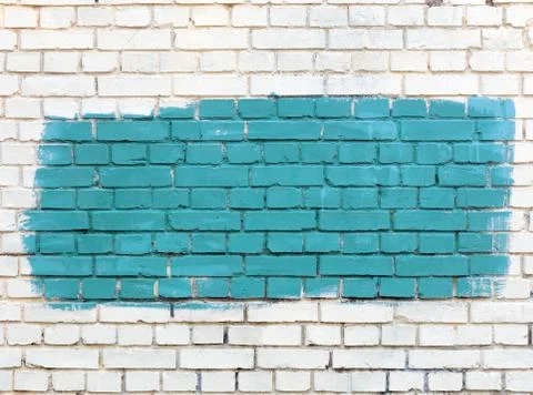On the white old brick wall the selected fragment is painted with green paint Stock Photos