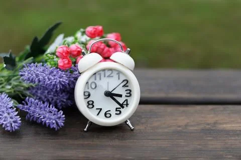White old clock alarm clock in the morning on nature on a wooden bench Foto stock