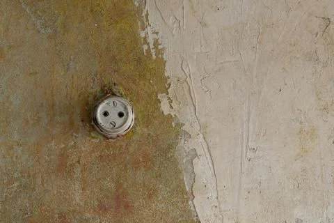 A white old soviet electric socket on a shabby stucco wall. Home repairs. Stock Photos