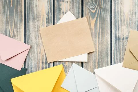 White open envelope with open kraft paper card on gray wooden background Stock Photos