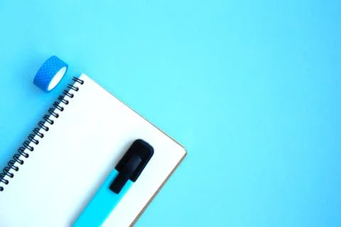 White open notebook with blue marker and scotch on a bright blue background Stock Photos
