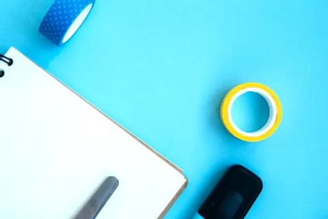 White open notebook with blue marker, scissors and scotch on a blue backgroun Stock Photos