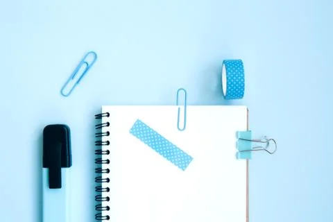 White open notebook with markers and scotch on a bright blue background Stock Photos