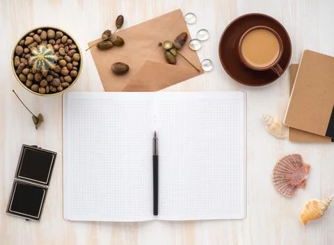 White open notepad, kraft envelope, cup of coffee and cactus in pot lying on Stock Photos