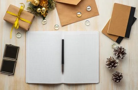 White open notepad, kraft envelope, and Christmas decoration lying on beige Stock Photos