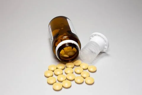 White open plastic jar with a bunch of white scattered pills on a light blue 写真素材