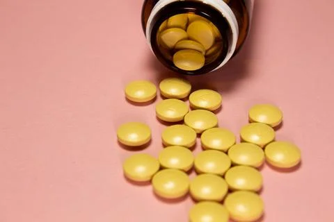 White open plastic jar with a bunch of white scattered pills on a light blue Stock Photos