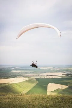White orange paraglide with a paraglider in a cocoon against the background of Stock Photos