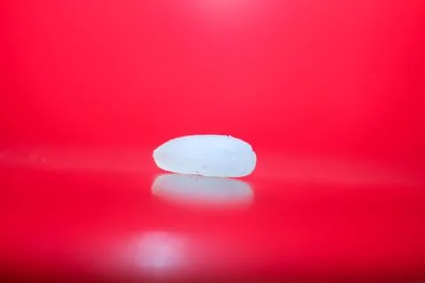 A white oval object on a red surface Stock Photos