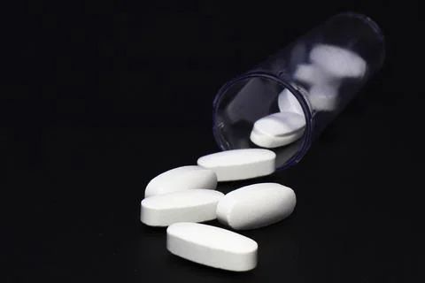 White oval tablets in a plastic container close up 写真素材