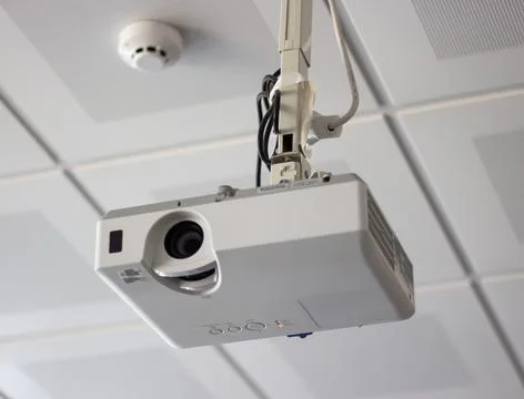 White overhead multimedia projector hanging on the ceiling in university Stock Photos