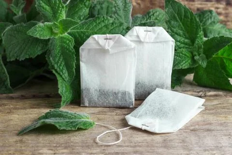White packages of disposable tea with mint branches on a wooden background Stock Photos