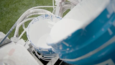 White paint being poured into spray paint bucket on equipment in football field Stock Footage 104769140