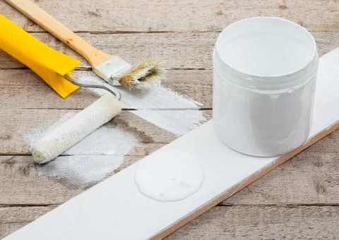 White paint with a brush or roller for painting wooden planks Stock Photos