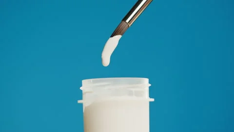 White paint isolated on blue background. Bright gouache falling from paintbrush 库存影片 178597960