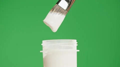 White paint isolated on green background. Gouache falling from paintbrush close Stock Footage 178592100
