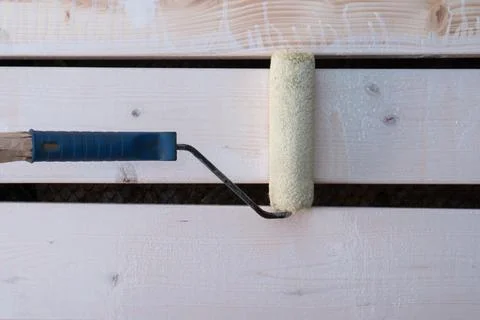 White paint roller applicator brush with handle painting wooden fence, floo.. Photos