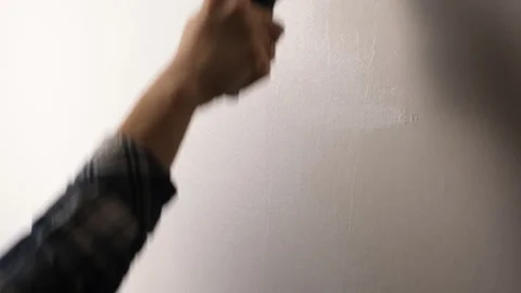 White paint roller moving vertically along the wall, applying a fresh layer of Stock Footage 312293268