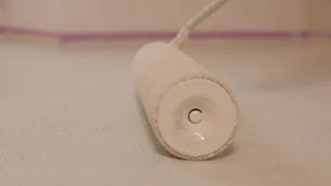 White Paint Roller Rolling on Floor Surface Stock Footage 345780225