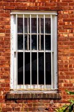 White painted window with security grill on old brick facade Stock Photos