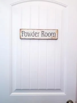 White panelled door with rustic rectangular wooden Powder Room sign Stock Photos