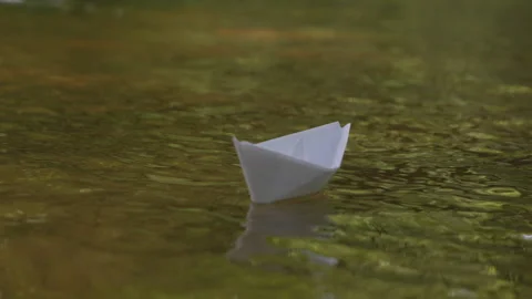 White paper boat floating on tranquil green river with soft ripples. A sing.. Video stock 330803801
