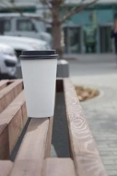 White paper coffee Cup with black plastic lid, outside. Coffee advertising Stock Photos