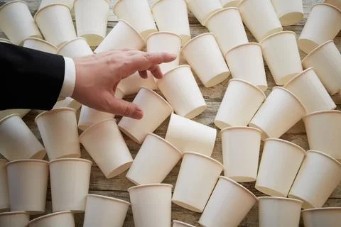 White paper cups scattered on the table in warm sunlight and a businessmans h Stock Photos
