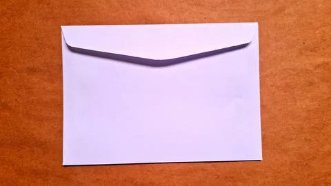 White paper envelope resting flat on a textured brown cardboard surface Stock Photos