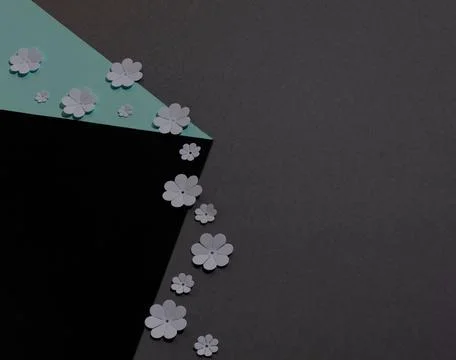White paper flowers falling from a cube against dark grey background. Paper art Stock Photos