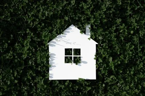 White paper house on a background of green leaves 스톡 사진
