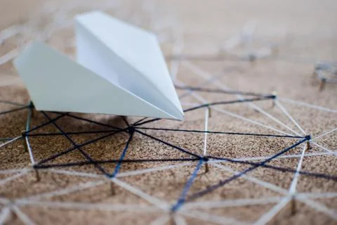 White paper plane over the threads linking the nails. Entities connected.  Stock Photos
